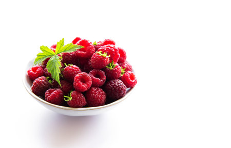 Fresh organic ripe raspberry with leaves on a white background