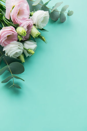 A beautiful composition featuring delicate pastel flowers alongside eucalyptus leaves is set against a vibrant turquoise backdrop. The fresh blooms create a serene and inviting atmosphere.の写真素材