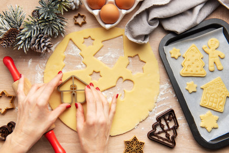 Woman preparing gingerbread cookies for christmas eve dinner using cookie cuttersの写真素材
