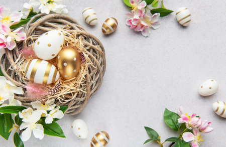 Easter eggs with gold and white decorations lying in a nest with spring flowers
