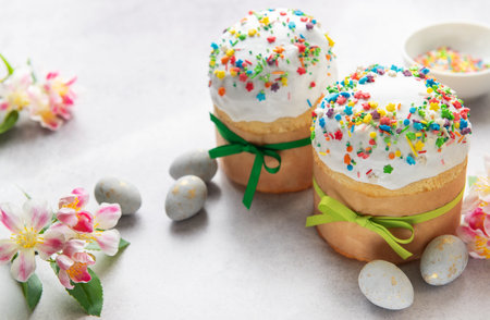 Traditional easter cakes decorated with colorful sprinkles and accompanied by painted eggs,...