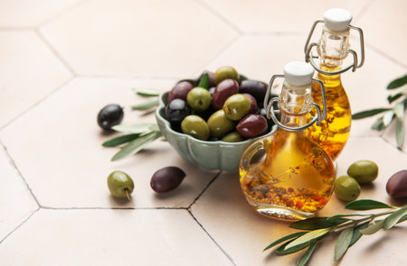 Assorted olives in bowl with olive oil bottles on tiled kitchen counterの写真素材