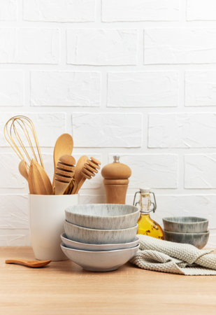 Wooden spoons, whisk, bowls, pepper mill, oil and folded dishcloth create cozy kitchen scene