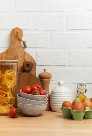 Kitchen counter displaying ingredients for delicious italian meal, including pasta, tomatoes, eggs, and olive oil, creating warm and inviting atmosphereの写真素材