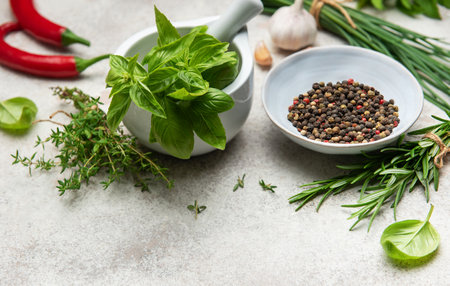 Aromatic herbs, spices, and colorful chili peppers arranged on a textured surface, ready to enhance culinary creationsの写真素材