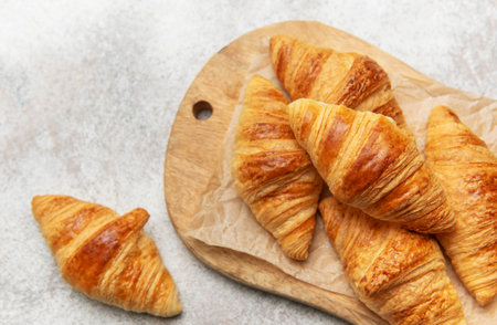 Golden croissants resting on a rustic wooden board