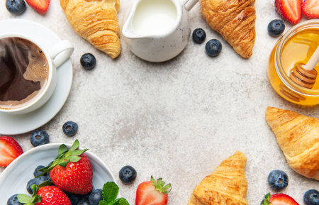 Delicious continental breakfast setting featuring freshly baked croissants, steaming coffee, vibrant berries, and golden honey, creating a tempting morning feastの写真素材