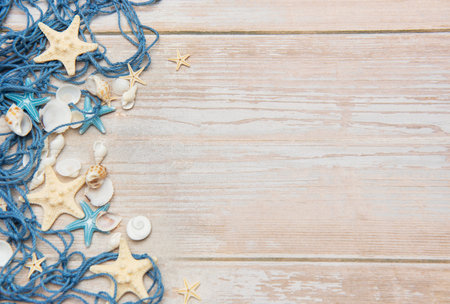 Decorative fishing net with starfishes and seashells lying on white wooden planks composing a summer background with copy spaceの写真素材