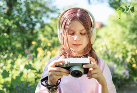 Teenage girl with pink hair taking pictures with her camera and listening music with headphones in a...