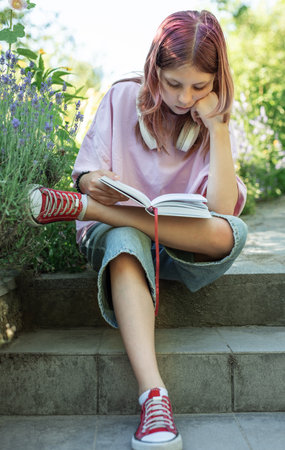 Young student is reading a book and enjoying her time outdoorsの写真素材