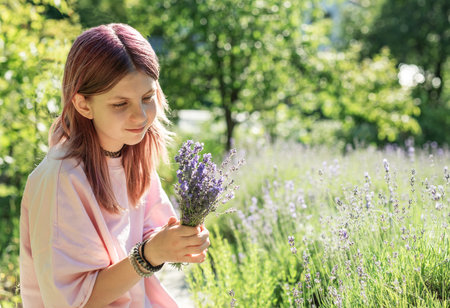 Girl enjoying the scent of a freshly picked bouquet of lavender in a fieldの写真素材