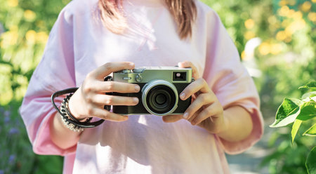 Woman capturing moments with a classic camera in a garden settingの写真素材