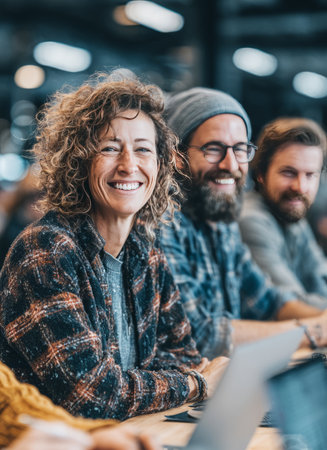 Creative people smiling and working together on laptops in coworking spaceの素材