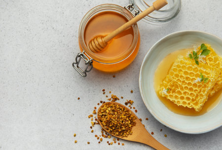 Golden honey, honeycomb and bee pollen are creating a delicious and healthy composition on a light backgroundの写真素材