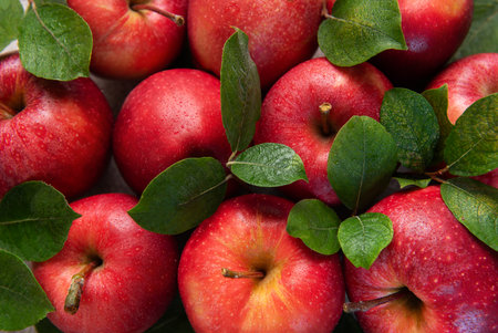Ripe red apples with green leaves create a vibrant and inviting display, perfect for showcasing...