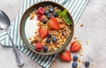 Granola in a bowl with yogurt, strawberries, blueberries, raspberries, and mint