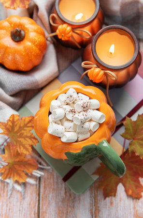 Pumpkin shaped mug filled with hot chocolate and marshmallows on an autumn backgroundの写真素材