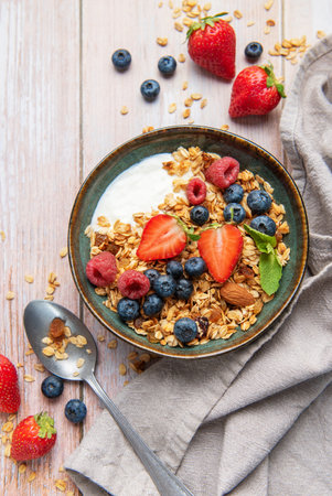Bowl of granola, yogurt, strawberries, blueberries, raspberries, and almonds for a healthy breakfastの写真素材
