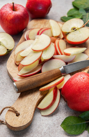 Fresh red apples, whole and sliced, on a wooden board with a knifeの写真素材