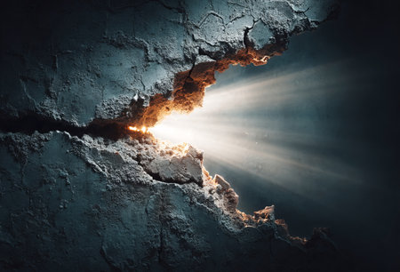 Broken concrete wall revealing a burst of light, symbolizing hope and breakthroughの素材
