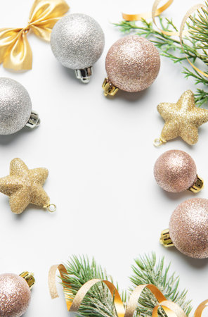 Sparkling christmas ornaments and green pine branches creating a festive border on white backgroundの写真素材