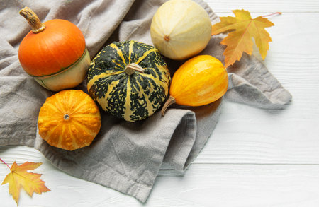 Gourds and maple leaves on a white wooden table expressing fall and thanksgivingの写真素材