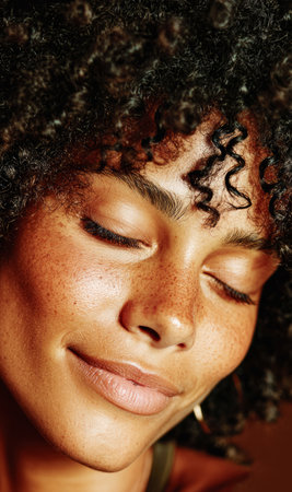 Young woman's face with closed eyes, showing freckles and curly hairの素材