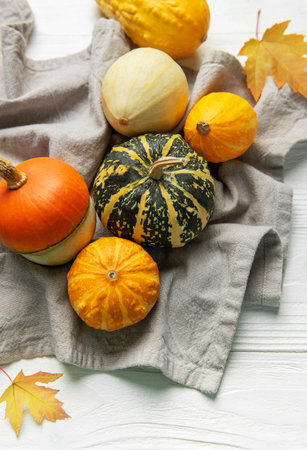 Gourds and maple leaves on a white wooden table expressing fall and thanksgivingの写真素材
