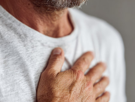 Senior man feeling a sharp chest pain, clutching his chestの素材