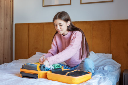 Young woman packing clothes in a suitcase, preparing for an adventureの写真素材