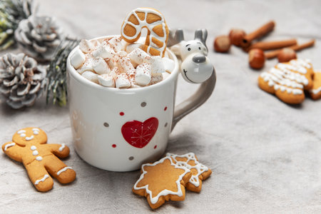 Reindeer mug filled with hot chocolate, marshmallows and gingerbread sweets with festive decor