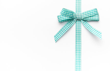 Teal and white checkered ribbon with a bow on a white backgroundの写真素材