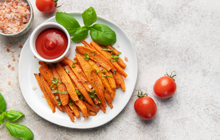 Plate of baked sweet potato fries, sprinkled with salt and fresh herbs