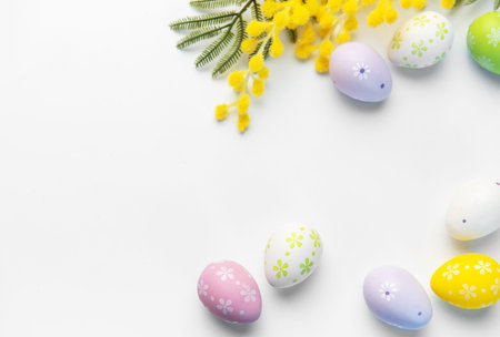 Delicate decorated eggs and mimosa branches creating a colorful spring border