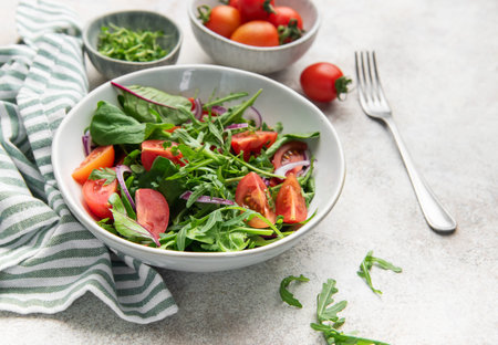 Bowl of organic arugula, spinach, tomato, and red onion salad
