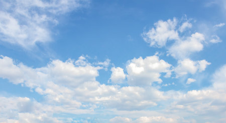 Vast blue sky adorned with soft white clouds, providing a tranquil backdrop, perfect for creative...