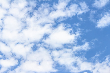 Expansive blue sky adorned with soft white clouds, creating a peaceful ambiance perfect for...