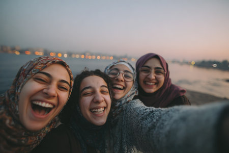 Women from Egypt are happily taking selfies by the Nile river, showcasing their joyful expressions and the beautiful sunset ambiance surrounding themの素材
