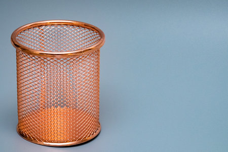 Copper mesh pencil holder, showcasing a cylindrical form and open weave, set against a soft blue backdrop, perfect for contemporary workspace aestheticsの写真素材
