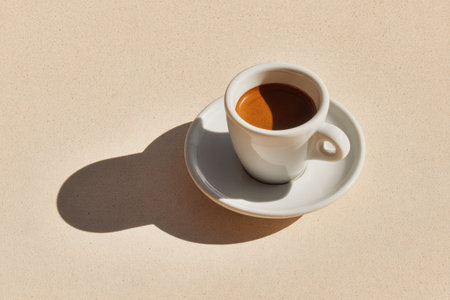 Minimalist photography of a white ceramic cup filled with espresso on a neutral background, highlighting the rich color and smooth texture of the coffeeの素材