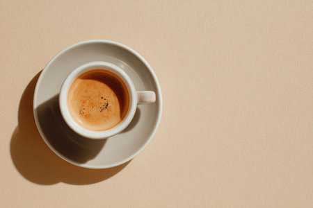 Minimalist composition featuring a flat white coffee in a stylish cup, set against a soft beige backdrop, highlighting warm tones and inviting ambianceの素材