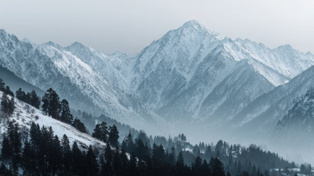 Photography captures snow-covered mountains partially veiled in mist, featuring soft tones and a calm aesthetic, inviting tranquility and reflection in nature's beautyの素材