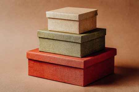 Three stacked gift boxes in natural colors showcase textured materials, arranged against a warm backdrop, ideal for holiday gifting and minimalist decor with copy spaceの素材