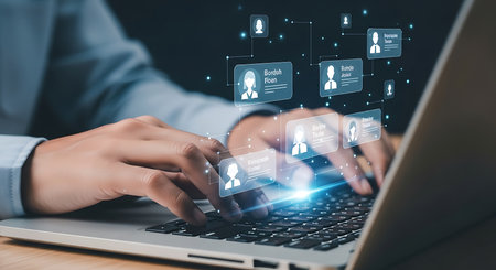 Hands typing on a laptop keyboard with glowing digital human profile icons representing online networking and connectionsの素材