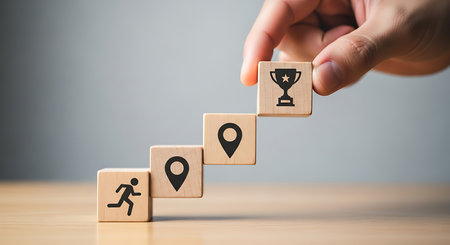 A hand places a wood cube block with a trophy icon on top, representing the concept of achieving business goals, success, and the journey towards victory.の素材