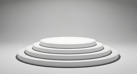 Minimalist white tiered stage pedestal with soft spotlight illumination against a neutral grey backgroundの素材