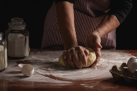 woman preparing dough with her hands on a dark backgroundの写真素材