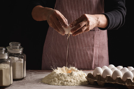 woman preparing dough with her hands on a dark backgroundの写真素材