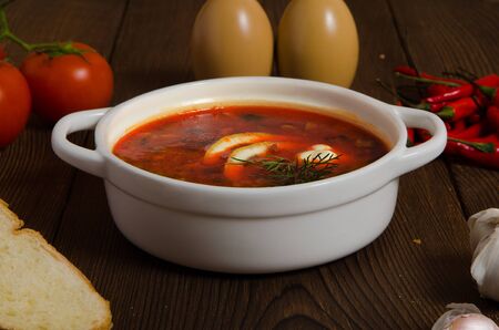 a bowl of soup with lemon slice, on wooden background garlic tomato
