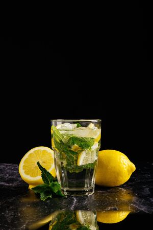 Fresh bright summer cocktail. Mojito cocktail with lime, lemon and mint in a glass on a fashionable stone background. Lemon mojitoの写真素材
